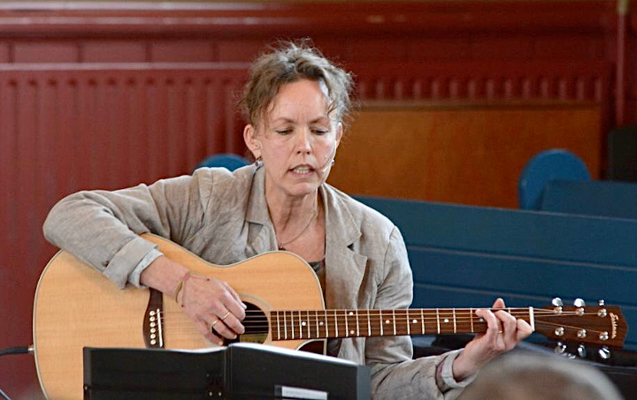 Aline Kruizenga spelend op een gitaar.